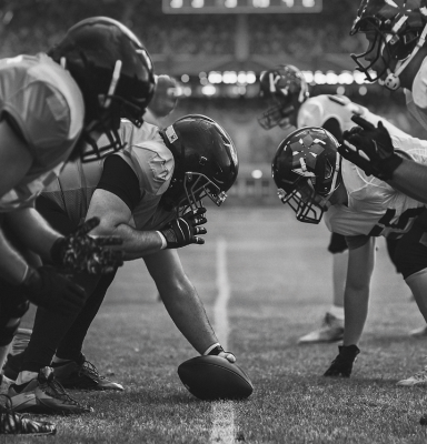 NFL players facing off with a football in the middle of the image.